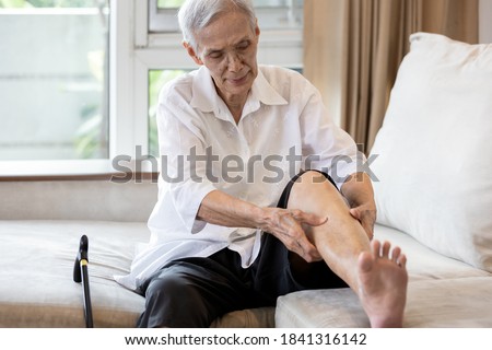 Asian senior woman hold her leg suffering from pain in legs,elderly patient have cramps in her calves,massage the calf by hands or beriberi in the leg,old people getting numb after sitting for so long
