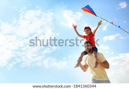 Happy father and his child playing with kite on sunny day. Spending time in nature Royalty-Free Stock Photo #1841360344