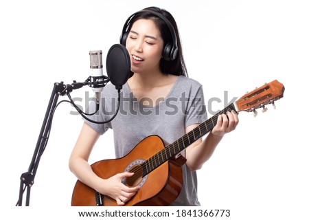 Young asian woman with microphone recording song and playing guitar in music studio, Woman performing in a recording studio for her album isolated on white background.
