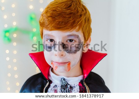 Horizontal portrait of little red haired boy dressed as a spooky vampire for Halloween. Halloween party trick or treat for children and family. Seasonal and festive concept.
