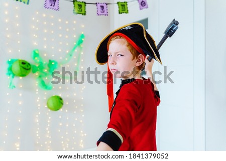 Horizontal view of little caucasian kid playing with Halloween pirate costume at home. Seasonal and festive Halloween party concept.