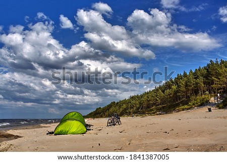 Bicycles parked by the green tent on a Baltic Sea beach in summer.