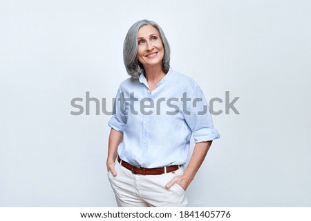 Happy dreamy mature senior business woman looking away at copy space and dreaming, planning. Smiling smart older 60s lady thinking of new opportunities vision standing isolated on grey background. Royalty-Free Stock Photo #1841405776