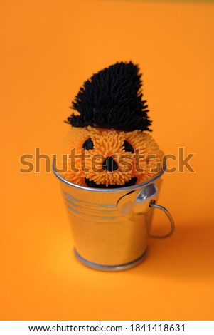 Halloween pumpkin with witch hat, in a bucket, on an orange background, halloween template design, isolated