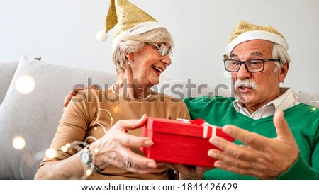 Seniors at New Year's Eve Party. Senior couple celebrating New Year together. They are sitting, laughing. Celebrating Christmas. Photo of senior couple on Christmas day