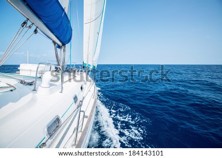 Sail boat with set up sails gliding in open sea at sunny day Royalty-Free Stock Photo #184143101