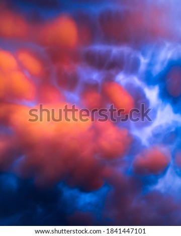 Red and orange clouds at sunset or sunrise with very curious shapes. Mammatus clouds. Strange and artistic sky clouds vertical background.