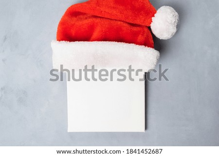 Mockup poster frame for Christmas message. Blank square canvas with Santa hat. Top view. Christmas concept.