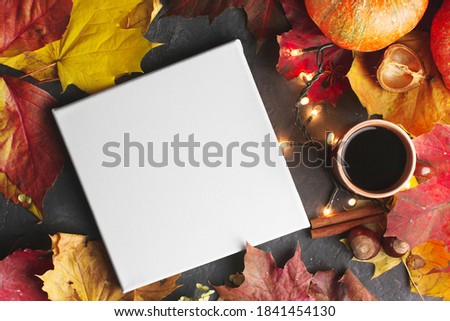 Cozy autumn background with blank canvas board, coffee and colourful maple leaves. Mockup poster, autumn concept. Top view.