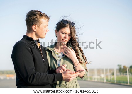 young couple of male and female looking photo from vacation, having fun outdoors
