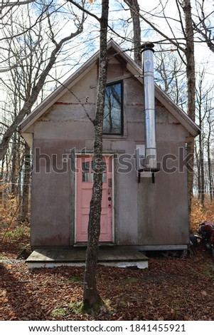 View of a sugar shack in the woods on private land, with several maple trees in Quebec, Canada
