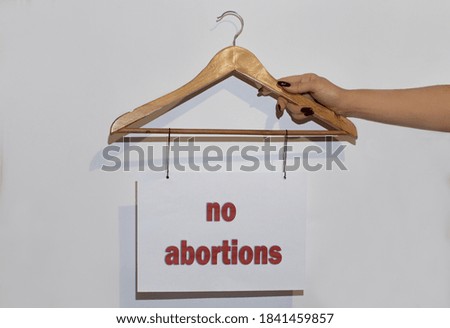 hand holds a banner with the inscription no abortions on a hanger