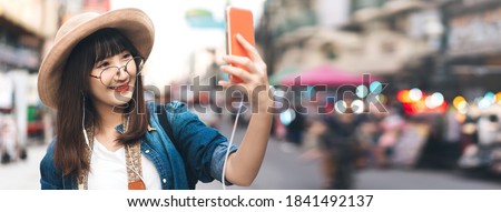 Happy young adult asian woman with modern lifestyle. Solo outdoor style backpack travel in city and using mobile phone digital media application for tourism. Banner size background