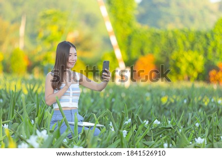 Woman using mobile phone to take photo in the flower garden.