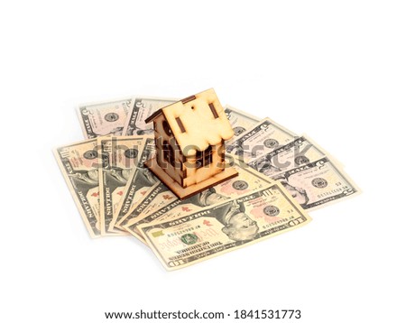 a wooden model of the house stands on a pile of american dollars as a symbol of mortgage investment