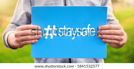Male teenager holds a banner with the word stay safe against nature background. Stay at home stay safe concept for coronavirus pandemic prevention.
