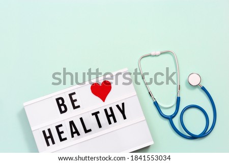 Healthcare and medical concept. Lightbox with words Be Healthy and stethoscope on blue colored background. Health wishes. Top view.