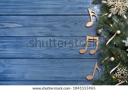 Fir tree branches with Christmas decor near decorative music notes and space for text on blue wooden background, flat lay