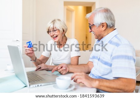 Excited senior woman looking at computer screen showing smiling middle aged husband online shopping sale on web site