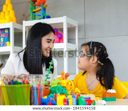 Asian girl with Down's syndrome play toy with her teacher in classroom. Concept disabled kid learning.