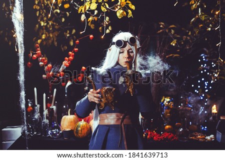 Halloween elf with magic magic in the dark forest. Beautiful young woman in a hat and elf costume holding magical chemistry. Halloween art design