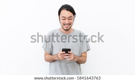 Portrait of happy young nerd asian man typing sms on smart phone isolated on white background. Technology communication with friends family work concept