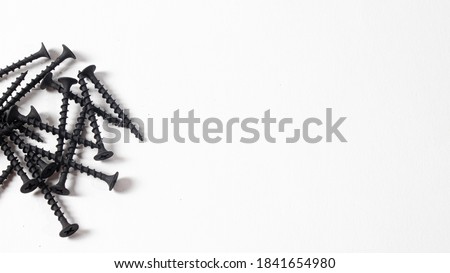 Self-cutters on a white background banner with copy space for text. Construction tools, self-tapping screws for fastening. Black screw hardware.