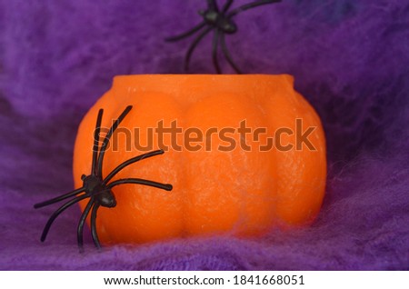 A black spider crawls on a purple web and an orange pumpkin on a lilac background. Halloween. Card. halloween pumpkin on a dark background