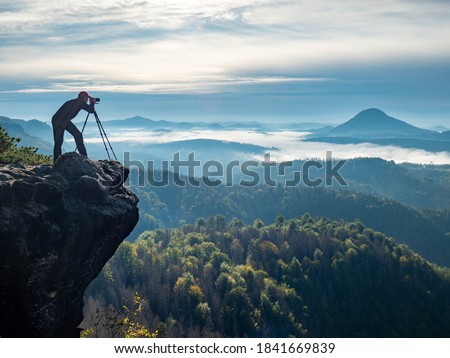 Silhouette of photographer in mountain.  Nature photographer traveler taking photo of beautiful morning landscape from top of the mountain Royalty-Free Stock Photo #1841669839