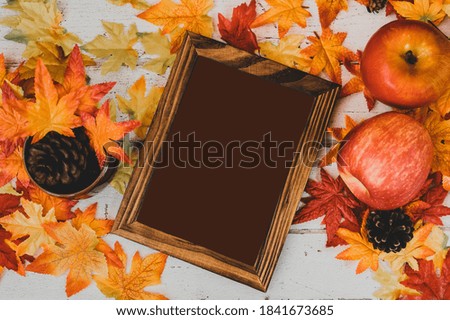 Autumn and Fall season. Empty photo frame and fake maple leaf on wood table. Harvest cornucopia and Thanksgiving day concept.