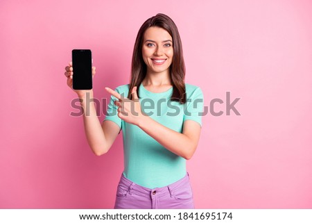 Photo portrait of girl pointing finger at blank space talking on phone isolated on pastel pink colored background