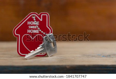 House keys with house shaped keychain on wooden background