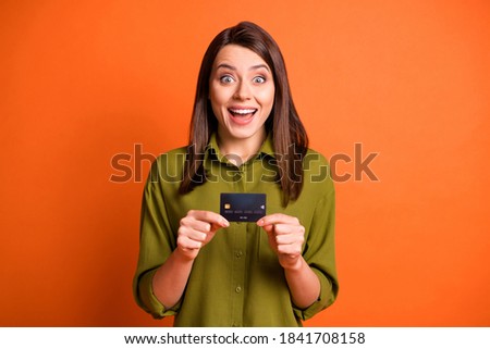 Photo of funky shocked girl hold plastic card look camera open mouth wear green shirt isolated orange color background