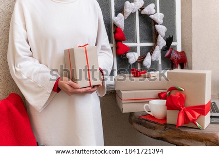 Woman's hands packing Gift's box with red ribbon on the eve of holidays Christmas and New Year.