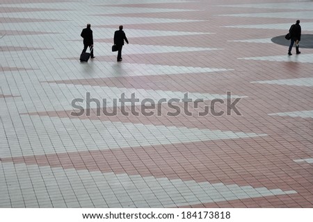 Three man is going away on empty square of airport