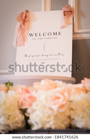 Wedding welcome sign with flowers. Orange and cream colors. Coral ribbons