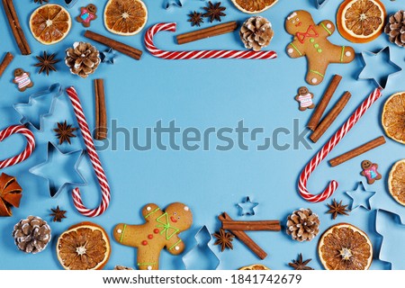 Christmas food frame. Gingerbread cookies, spices and decorations on blue background with copy space