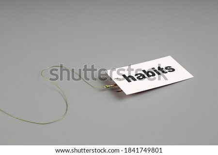 white card with the inscription hobby is attached to a fishing hook. addiction to your hobby