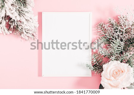 Christmas, winter composition. Photo frame, fir tree branches, flowers on pastel pink background. Christmas, New Year, winter concept. Flat lay, top view, copy space