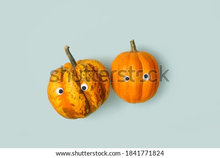 cute pumpkins on blue background. symbol of Halloween. orange pumpkins with google eyes, funny faces, kawaii characters. autumn festive season. top view