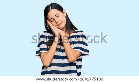 Beautiful young woman wearing casual clothes sleeping tired dreaming and posing with hands together while smiling with closed eyes. 