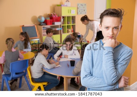 Portrait of upset schoolboy, boys and girls in classroom