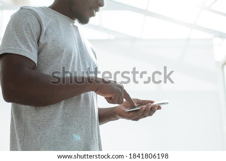 close up. smiling guy choosing a contact on his smartphone