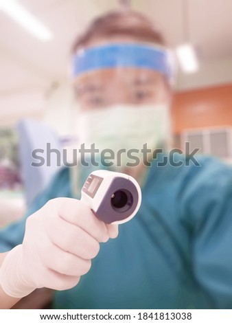 Selective focus of Infrared thermometer on blurred background. of asian woman doctor or nurse.