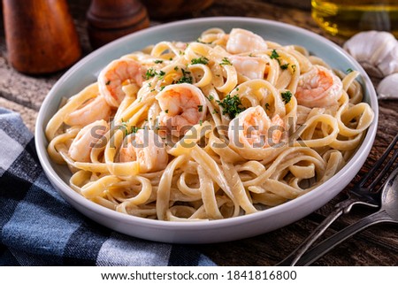 A plate of delicious shrimp alfredo with garlic and cream sauce over pasta. Royalty-Free Stock Photo #1841816800