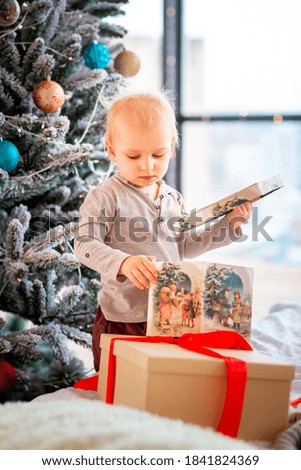 Happy little baby boy opening present boxes near Christmas tree. Christmas morning concept