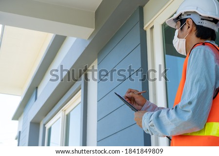 Engineers or inspectors in orange reflective vests are taking notes and checking with clipboards at the building's construction site, contractor inspections and engineering concepts. Royalty-Free Stock Photo #1841849809