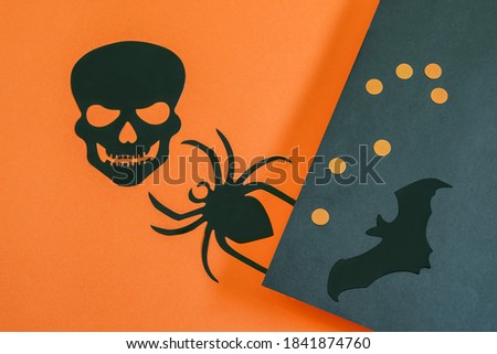 Decorative scull, spider and bat animal on the black-orange paper Halloween background.