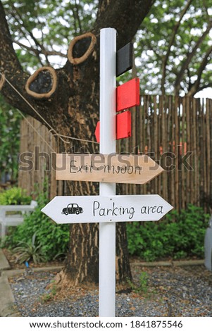 Direction parking area sign on wooden panel with arrow on the pole.