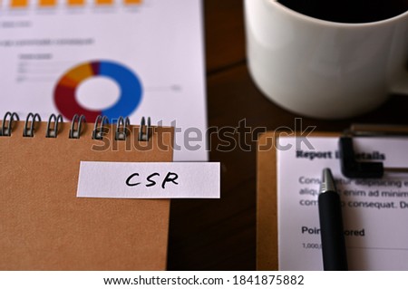 There is a laptop, a cup of coffee, and a sticky note with the word CSR written on it. It was an abbreviation for corporate social responsibility.
